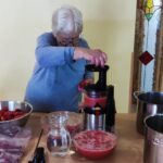 Starejša ženska med pripravo rdečega napitka.