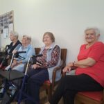 Štiri starejše ženske sedijo na stolih.