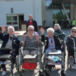 Skupina starejših žensk sedi na invalidskih vozičkih.