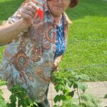 Starejša gospa v rokah drži sadež.