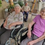 Dve starejši ženski sedita na invalidskih vozičkih.