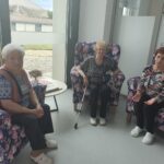 Tri starejše ženske sedijo na počivalnikih.