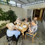 Štiri starejše ženske in moški sedijo pri mizi in jedo zajtrk.