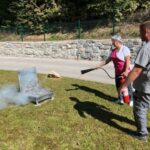 Zaposlena na vaji požarne varnosti uporablja gasilni aparat za gašenje simuliranega požara na prostem.